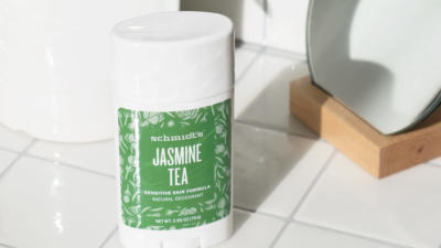 Schmidt's Jasmine Tea sensitive skin deodorant stick on a white tile countertop in front of a plant and a mirror